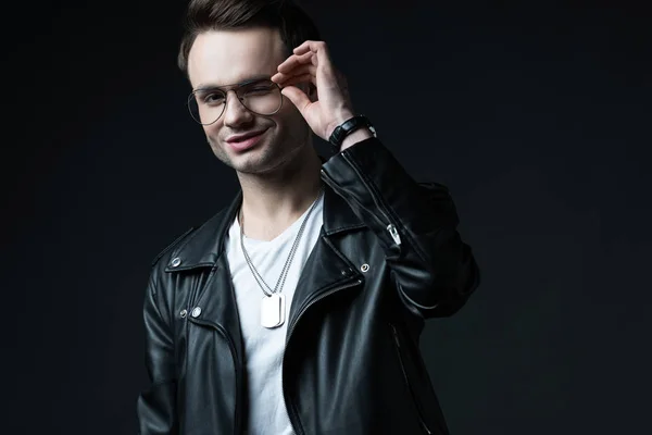 Smiling Stylish Brutal Man Biker Jacket Touching Eyeglasses Isolated Black — 스톡 사진