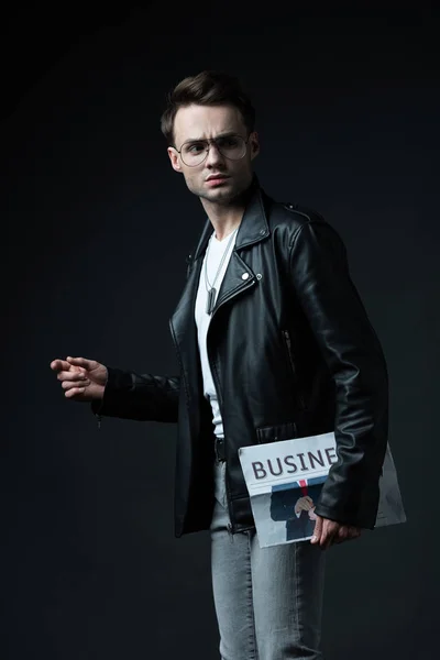 黒で隔絶されたビジネス新聞とバイカージャケットの深刻なスタイリッシュな残忍な男 — ストック写真