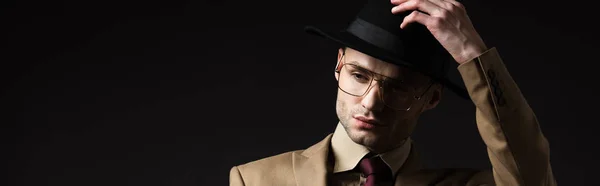 Homem Elegante Terno Bege Óculos Colocando Chapéu Isolado Preto Tiro — Fotografia de Stock