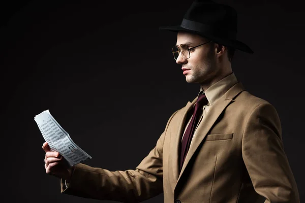 ベージュのスーツを着たエレガントな男の側面図帽子と眼鏡を読む新聞黒で隔離された — ストック写真