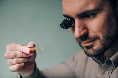 Gözlüklü yakışıklı saatçi. Hoparlör kolundaki saat. Gri kısımda izole edilmiş.