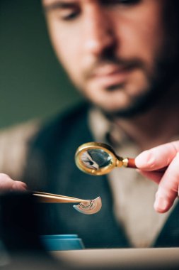 Saat tamircisinin seçici odak noktası masalarda cımbız ve büyüteç parçalarıyla çalışmak