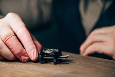 Masadaki hareket tutucuyu tutan lateks parmaklı saatçinin kırpılmış görüntüsü