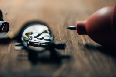Selective focus of wristwatch, magnifying glass and blower on wooden table clipart