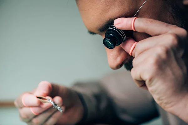 眼鏡のルーペを保持し 部品を見てラテックス指先で時計メーカーの側面図 — ストック写真