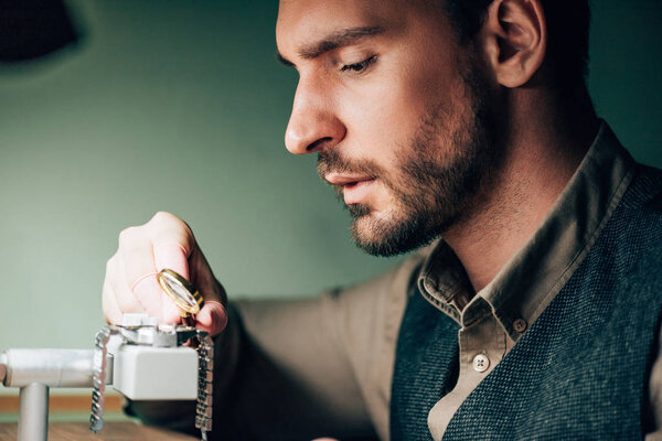 Side view of watchmaker using with magnifying glass for wristwatch on movement holder