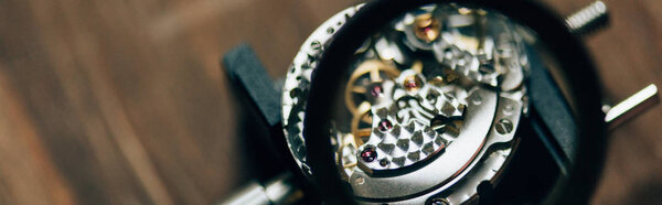 Selective focus of magnifying glass and open wristwatch on table, panoramic shot 