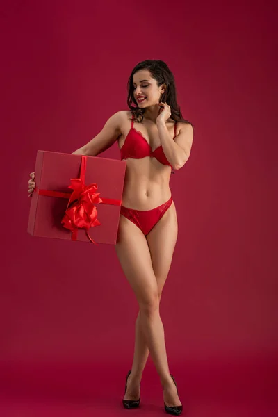 穿着内衣和高跟鞋的性感 微笑的女孩 手里拿着红色背景的大礼品盒 上面有彩带和蝴蝶结 — 图库照片