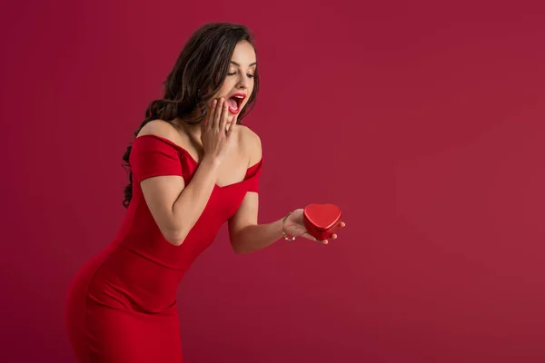 Sorprendida Elegante Chica Tocando Cara Mientras Sostiene Caja Regalo Forma — Foto de Stock