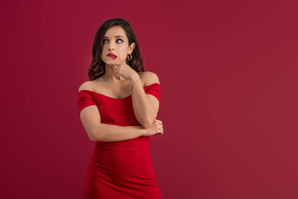 dreamy, elegant girl looking away while standing isolated on red