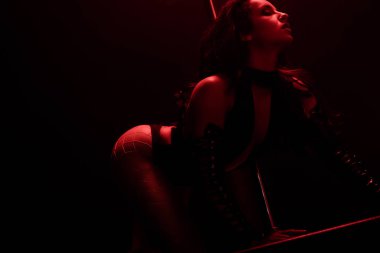 red lighting on passionate stripper dancing near pylon isolated on black with red lighting  clipart
