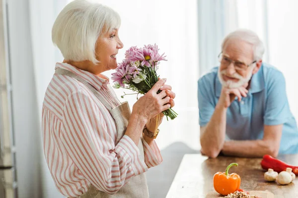 テーブルの上に野菜で花束と笑顔の夫と笑顔の女性の選択的な焦点 — ストック写真