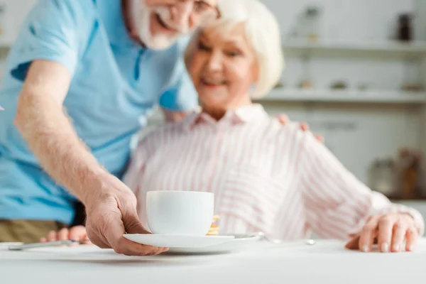 Selective Focus Senior Man Putting Coffee Cup Smiling Wife Table — 스톡 사진