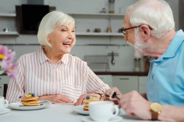 老年夫妇在厨房吃早餐时互相微笑的选择性焦点 — 图库照片