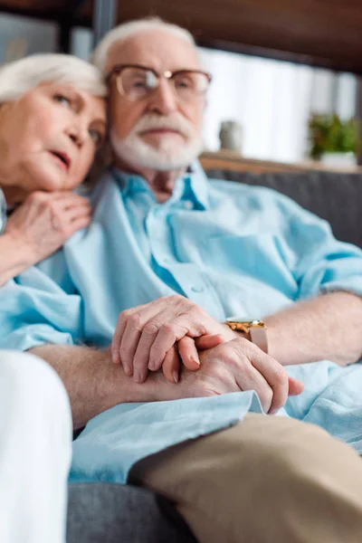 Selektivní Zaměření Seniorského Páru Držícího Ruce Zatímco Sedí Doma Pohovce — Stock fotografie