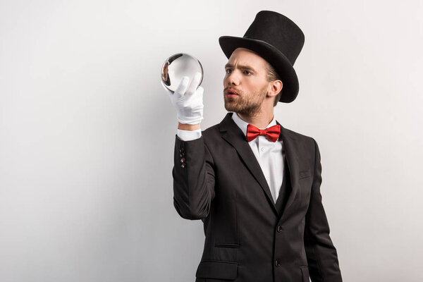 interested professional magician holding magic ball, isolated on grey