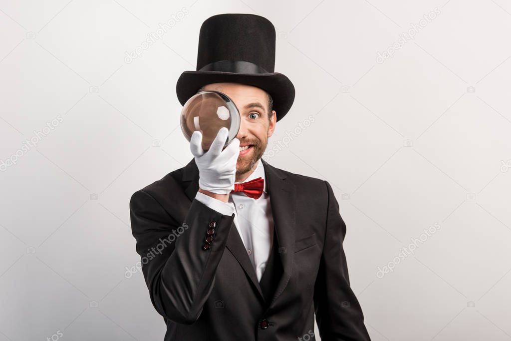 professional magician holding magic ball, isolated on grey