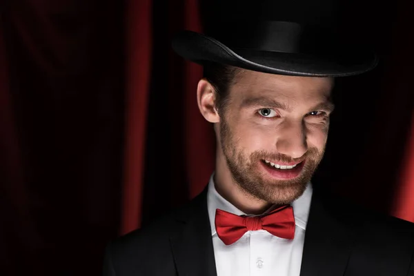 スーツを着た怖い笑顔のプロの魔術師と赤いカーテンのサーカスの帽子 — ストック写真