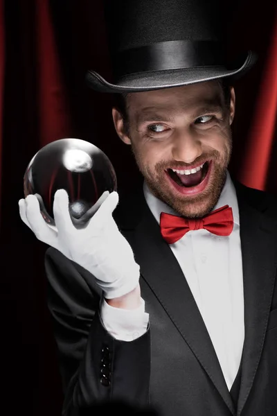 兴奋的可怕魔术师拿着魔术球在红色窗帘的马戏团里表演 — 图库照片