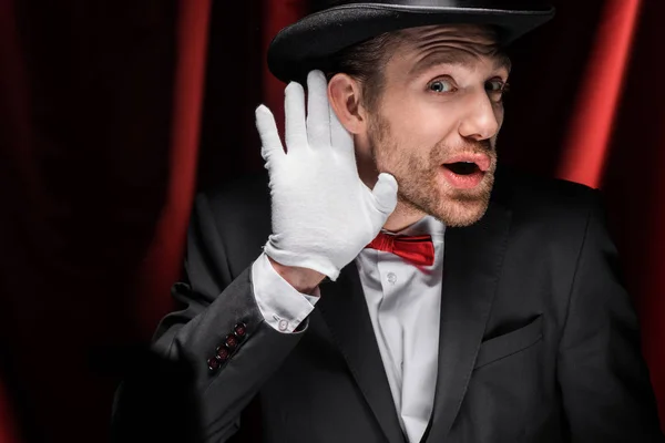 魔术师用红色窗帘在马戏团里打手势和听 — 图库照片