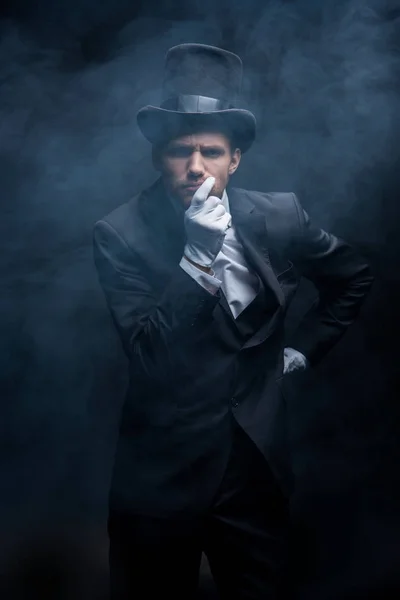スーツを着た思慮深い魔術師と暗い煙の部屋に立つ帽子 — ストック写真