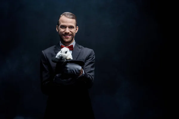 Mágico Sorrindo Segurando Coelho Branco Chapéu Isolado Preto — Fotografia de Stock