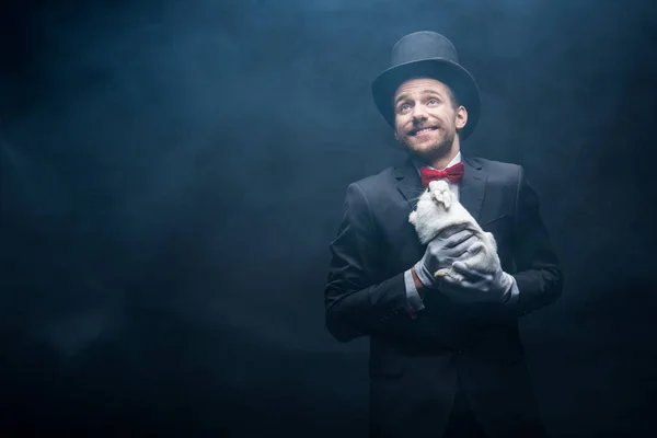 Feliz Mago Emocional Traje Sombrero Sosteniendo Conejo Blanco Cuarto Oscuro — Foto de Stock