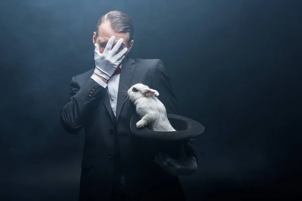 Scared Magician Closing Face Holding White Rabbit Hat Dark Room — 스톡 사진