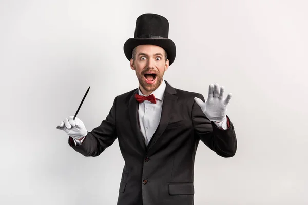 兴奋的魔术师 身穿西服 头戴帽子 手持魔杖 与灰色隔离 — 图库照片