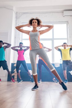 Çok ırklı zumba dansçılarının seçici odağı dans stüdyosunda Afrikalı Amerikalı antrenörle egzersiz yapıyor. 