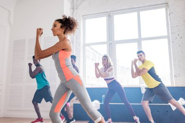 Afrika kökenli Amerikalı antrenörün seçici odak noktası dans stüdyosunda çok ırklı zumba dansçılarıyla hareketler çalışması.