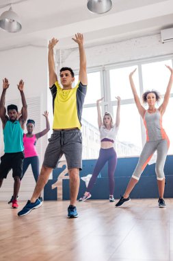 Antrenör ve çok kültürlü dansçıların seçmeli odağı dans stüdyosunda zumba yapıyor.