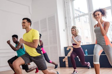 Gülümseyen çoklu etnik dansçılar dans stüdyosunda zumba yapıyorlar.