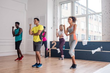 Gülümseyen çok kültürlü dansçılar dans stüdyosunda zumba hareketleri yapıyorlar.