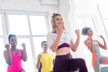 Dans stüdyosunda birlikte zumba yapan gülümseyen çok kültürlü dansçıların düşük açılı görüntüsü.
