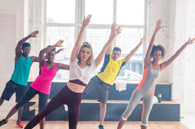 Dans stüdyosunda elleri hava eğitiminde olan çok kültürlü zumba dansçılarının seçici odağı.