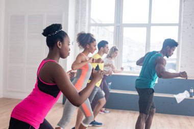 Çok kültürlü dansçıların Afrika kökenli Amerikalı bir eğitmenle dans stüdyosunda zumba hareketleri öğrenmesi.