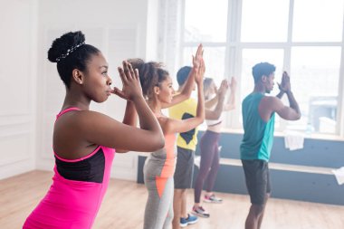 Çok kültürlü zumba dansçılarının seçici odak noktası dans stüdyosunda Afrikalı Amerikalı antrenörle pratik yapmak.