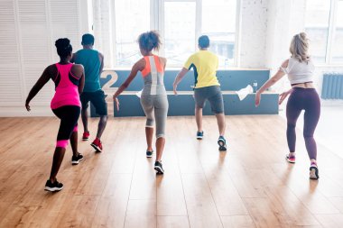 Dans stüdyosunda birlikte zumba yapan genç çok kültürlü dansçıların arka planı.