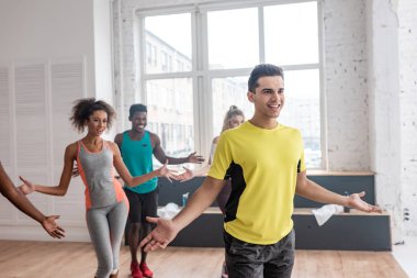 Gülümseyen çoklu etnik dansçılar ve antrenör dans stüdyosunda zumba yapıyor.