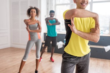 Dans stüdyosunda Afrikalı Amerikalı dansçılarla zumba yapan gülümseyen antrenörün seçici odağı.