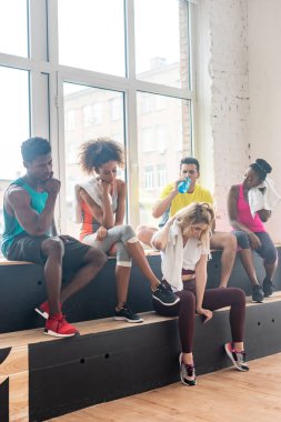 Çok kültürlü zumba dansçıları dans stüdyosunda çalışırken dinleniyorlar.