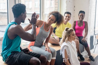 Gülümseyen Afro-Amerikan zumba dansçıları dans stüdyosunda dinlenirken beşlik çakıyor.