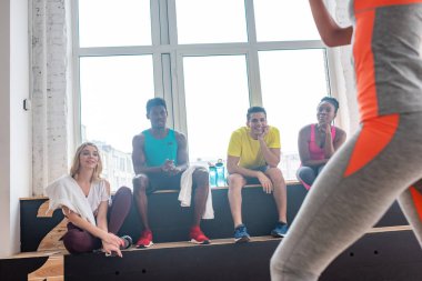 Selective focus of multicultural zumba dancers looking at girl exercising in dance studio  clipart
