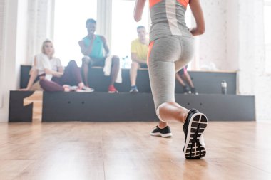 Seçici odak noktası, dans stüdyosundaki kürsüde çok kültürlü zumba dansçılarıyla ısınmak.