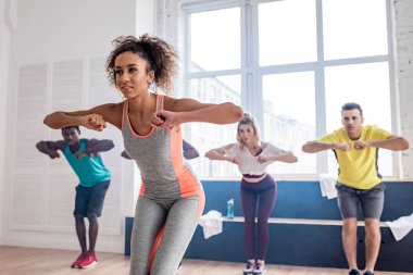 Afrika kökenli Amerikalı eğitmenin seçici odağı dans stüdyosunda zumba dansçılarının hareketleriyle eğiliyor.