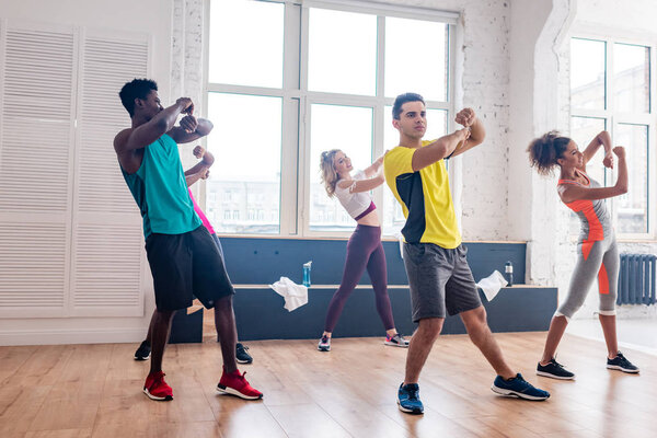 Young multicultural zumba dancers exercising movements in dance studio 
