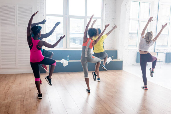 Back view of multicultural dancers exercising zumba in dance studio