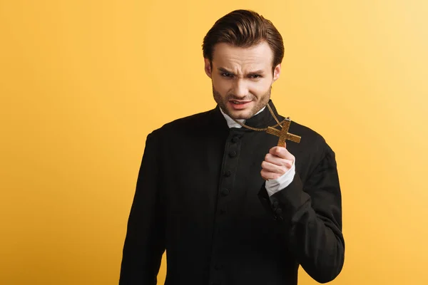 Сердитый Католический Священник Показывает Крест Глядя Камеру Изолированную Желтый — стоковое фото