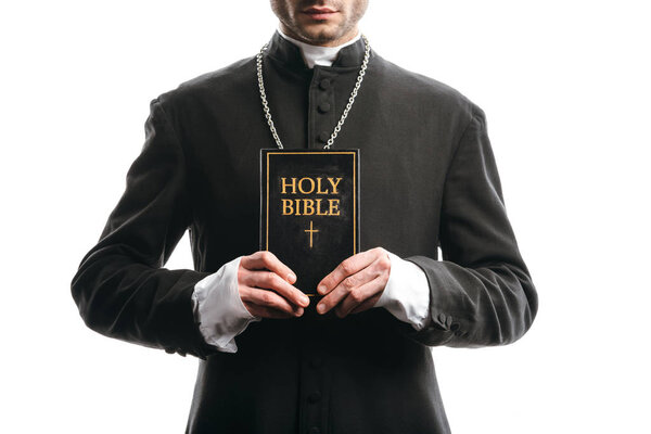 cropped view of catholic priest holding holy bible isolated on white